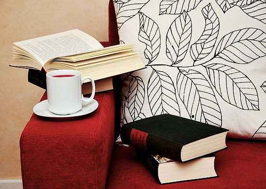 Rotes Sofa mit Kaffee und Büchern auf der Armlehne